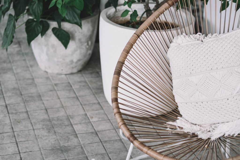 white pillow on brown chair beside plants